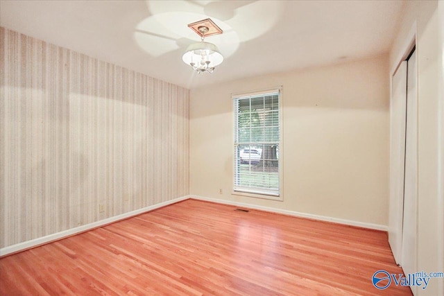 210 Spring Valley Ct SW, Huntsville, AL 35802 - empty room with wood finished floors, a chandelier, and wallpapered walls