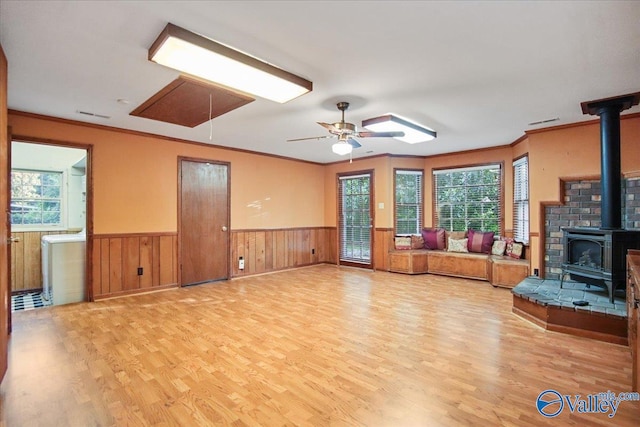 210 Spring Valley Ct SW, Huntsville, AL 35802 - unfurnished living room with attic access, a wood stove, wood finished floors, wainscoting, and healthy amount of natural light