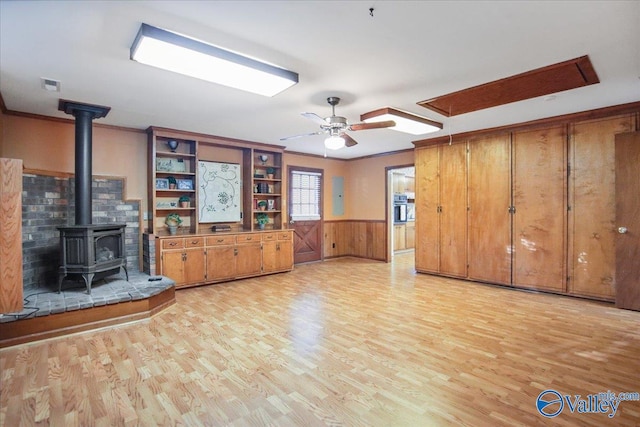 210 Spring Valley Ct SW, Huntsville, AL 35802 - unfurnished living room with a wood stove, light wood-type flooring, wainscoting, a ceiling fan, and ornamental molding