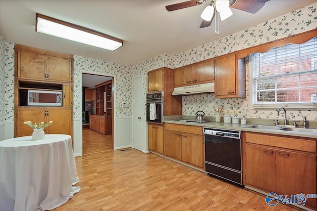 210 Spring Valley Ct SW, Huntsville, AL 35802 - kitchen with wallpapered walls, black appliances, under cabinet range hood, light wood-type flooring, and brown cabinets