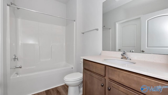 full bathroom with hardwood / wood-style flooring, washtub / shower combination, vanity, and toilet