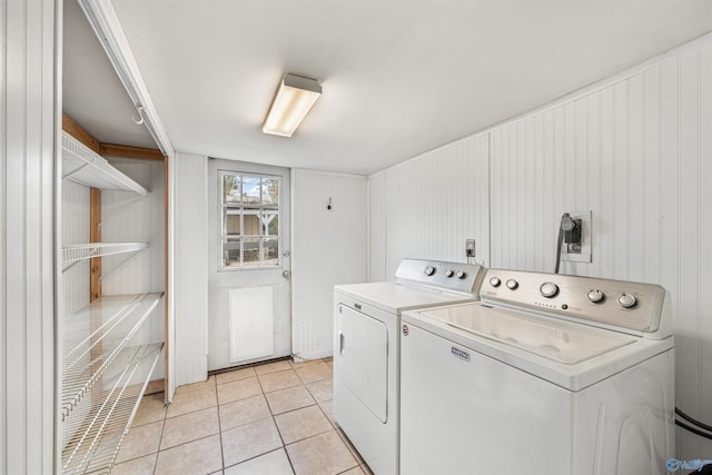 washroom featuring washing machine and clothes dryer, wood walls, and light tile patterned flooring