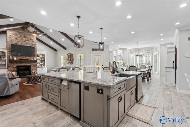 kitchen featuring a spacious island, hanging light fixtures, gray cabinetry, open floor plan, and light stone countertops