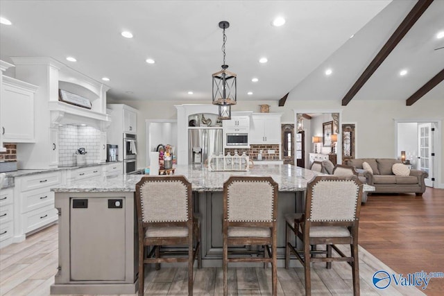 kitchen featuring appliances with stainless steel finishes, a spacious island, decorative light fixtures, and white cabinets