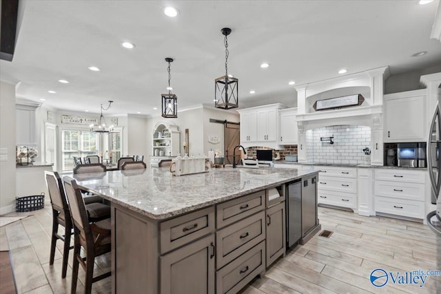 kitchen featuring light stone counters, a large island, hanging light fixtures, backsplash, and white cabinetry