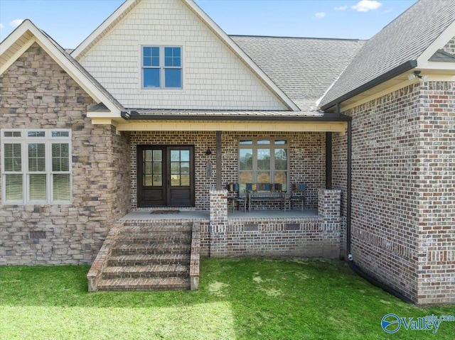 entrance to property with french doors, a yard, a standing seam roof, metal roof, and stone siding