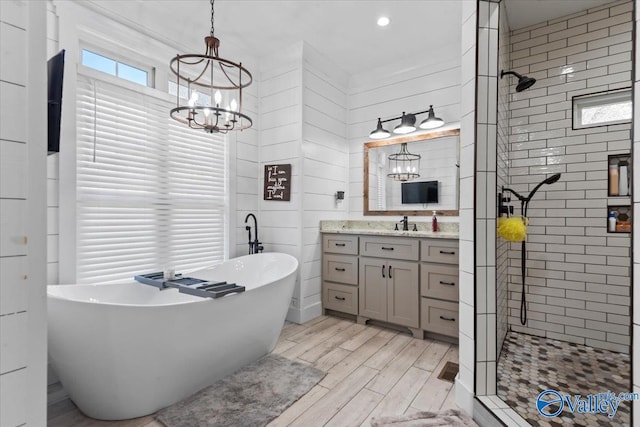 bathroom featuring a soaking tub, a stall shower, vanity, wood finished floors, and plenty of natural light