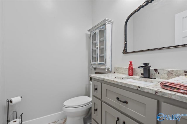 bathroom featuring toilet, vanity, and baseboards