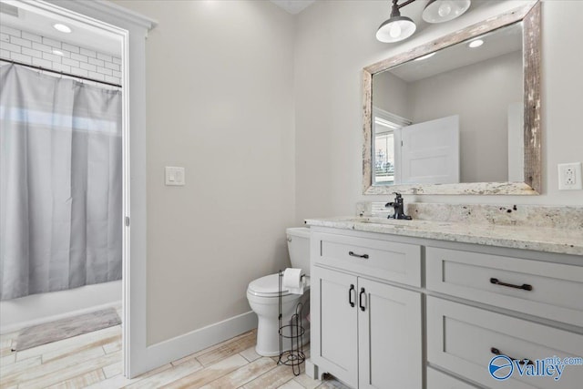 full bath with toilet, wood finished floors, vanity, and baseboards