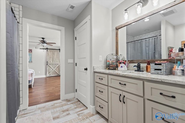 bathroom with visible vents, wood finished floors, a ceiling fan, and vanity