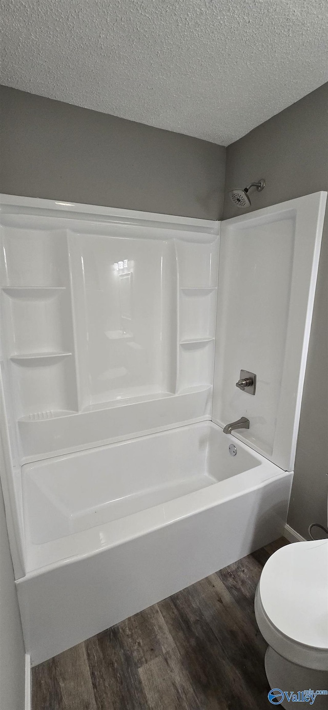 bathroom with hardwood / wood-style floors,  shower combination, toilet, and a textured ceiling