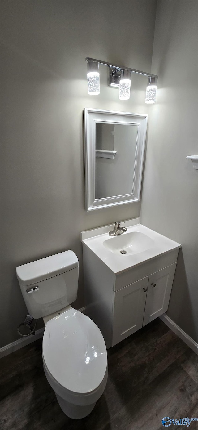 bathroom featuring toilet, vanity, and hardwood / wood-style flooring