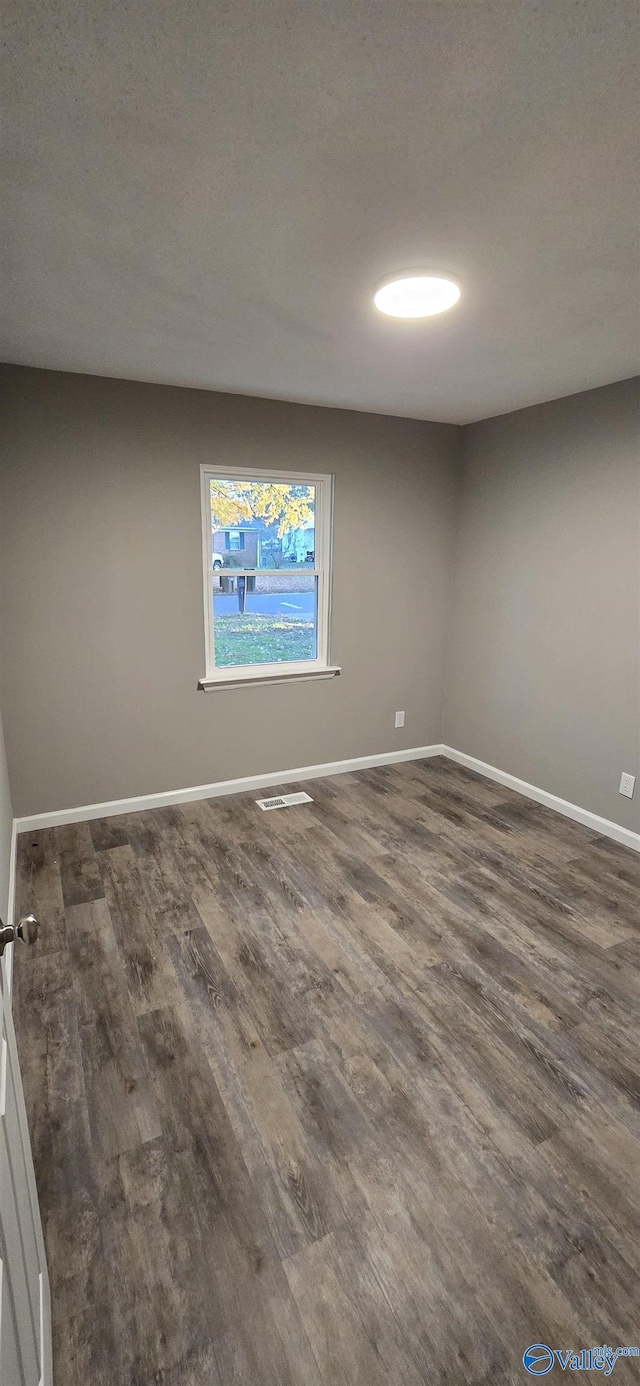 spare room featuring a textured ceiling and dark hardwood / wood-style floors