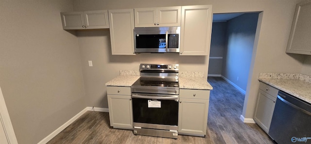 kitchen featuring light stone counters, dark wood-type flooring, and appliances with stainless steel finishes