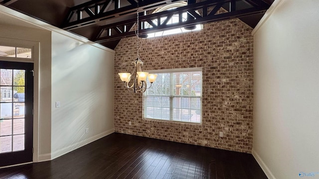 unfurnished dining area with brick wall, dark wood-type flooring, and an inviting chandelier