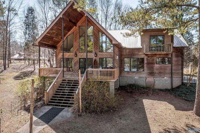 rear view of house featuring stairs and metal roof