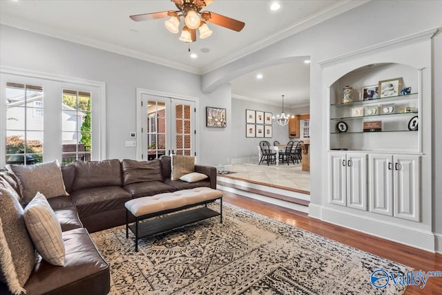 living room featuring french doors, ornamental molding, light wood-type flooring, and ceiling fan with notable chandelier