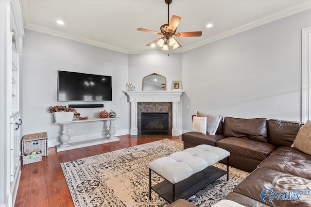 living room featuring ornamental molding, dark wood-type flooring, a tiled fireplace, and ceiling fan