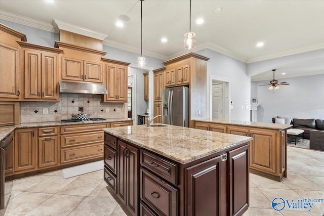 kitchen with an island with sink, hanging light fixtures, stainless steel appliances, ornamental molding, and ceiling fan