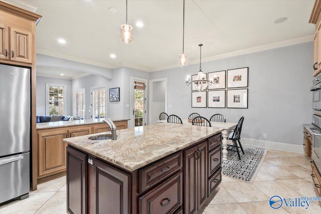 kitchen featuring appliances with stainless steel finishes, sink, decorative light fixtures, crown molding, and a center island with sink