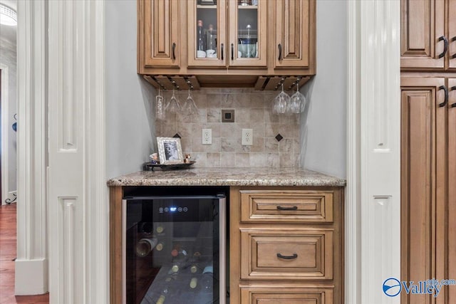 bar with hardwood / wood-style floors, wine cooler, tasteful backsplash, and light stone countertops