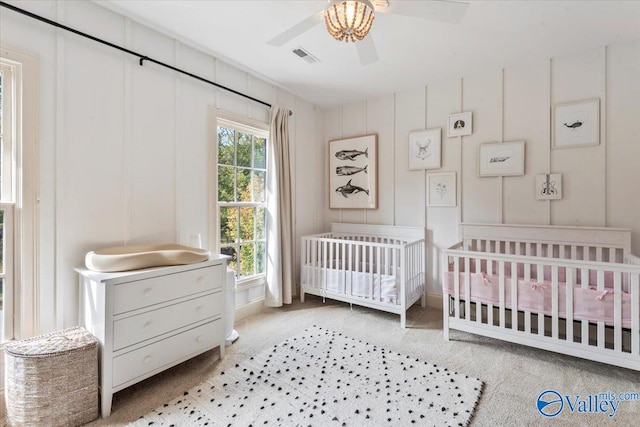 bedroom featuring light colored carpet, a crib, and ceiling fan