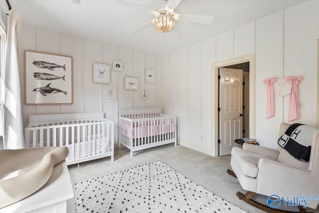 carpeted bedroom with a nursery area and ceiling fan