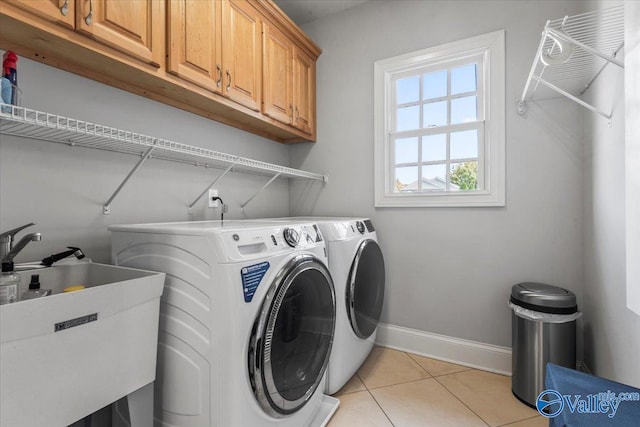 washroom featuring sink, light tile patterned flooring, cabinets, and washer and clothes dryer