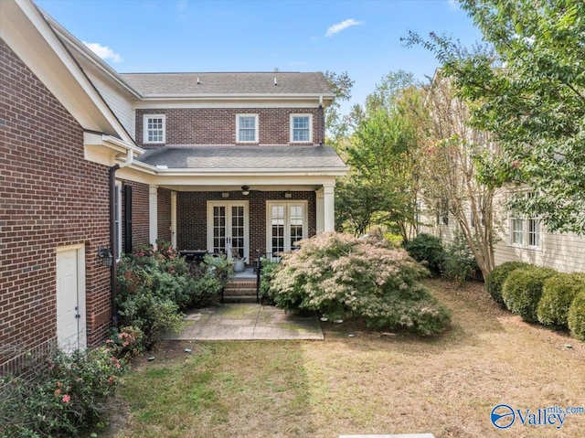 view of exterior entry with covered porch, a lawn, and ceiling fan