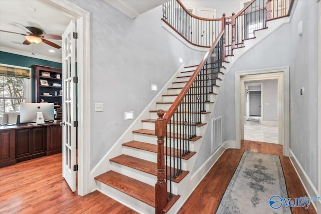 stairs with ornamental molding, french doors, and hardwood / wood-style floors