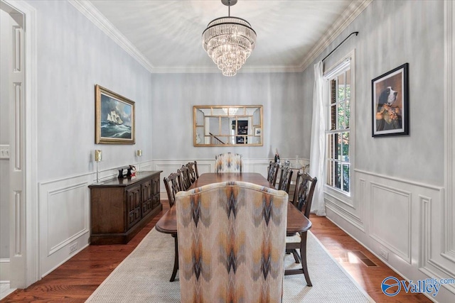 dining area featuring ornamental molding, hardwood / wood-style flooring, and an inviting chandelier