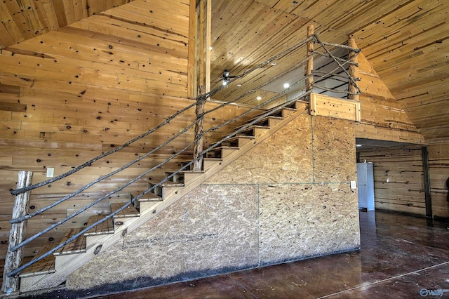 stairway featuring wooden ceiling, high vaulted ceiling, and wood walls