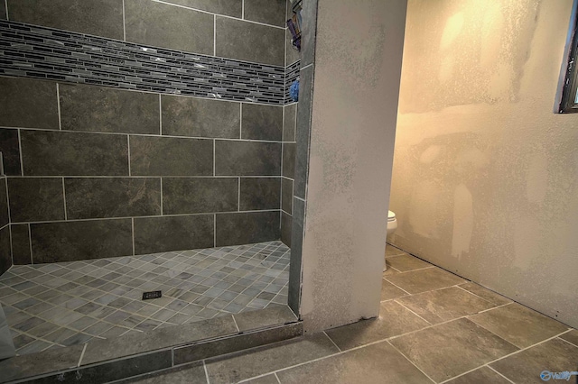 bathroom with toilet and tiled shower