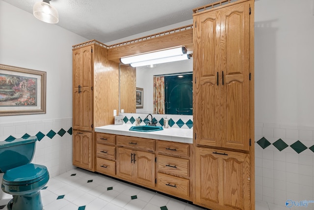 bathroom with tile patterned flooring, tile walls, toilet, and vanity