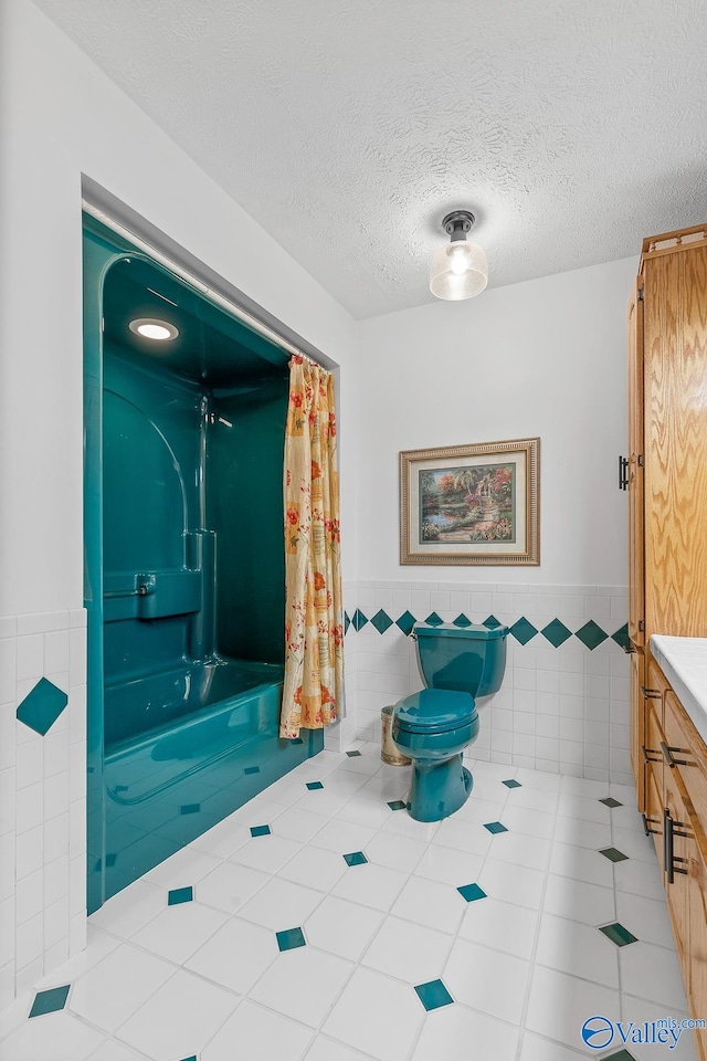 bathroom featuring vanity, a textured ceiling, toilet, and tile walls