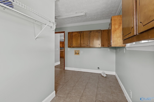 laundry area with electric dryer hookup, cabinets, hookup for a washing machine, a textured ceiling, and light tile patterned floors