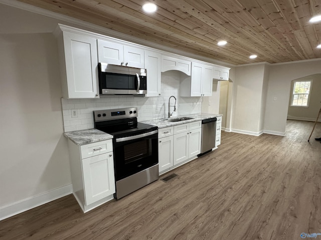 kitchen with appliances with stainless steel finishes, light stone countertops, sink, and white cabinets