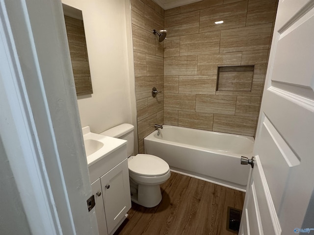 full bathroom with vanity, tiled shower / bath, hardwood / wood-style floors, and toilet