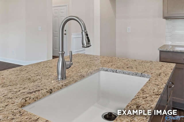 interior details with sink, light stone counters, and backsplash