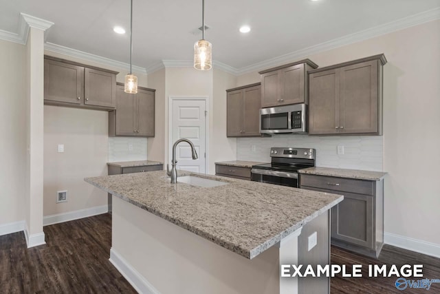 kitchen featuring sink, an island with sink, light stone counters, and stainless steel appliances