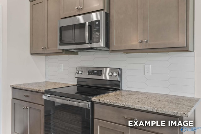 kitchen with appliances with stainless steel finishes, decorative backsplash, and light stone countertops