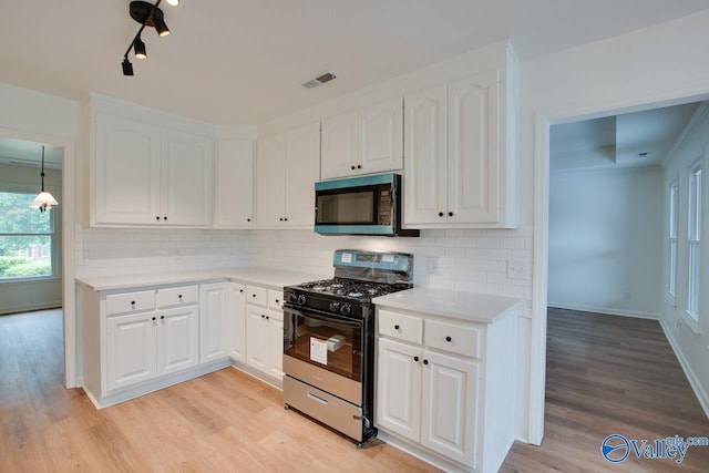 kitchen with white cabinetry, visible vents, gas range oven, and light wood finished floors