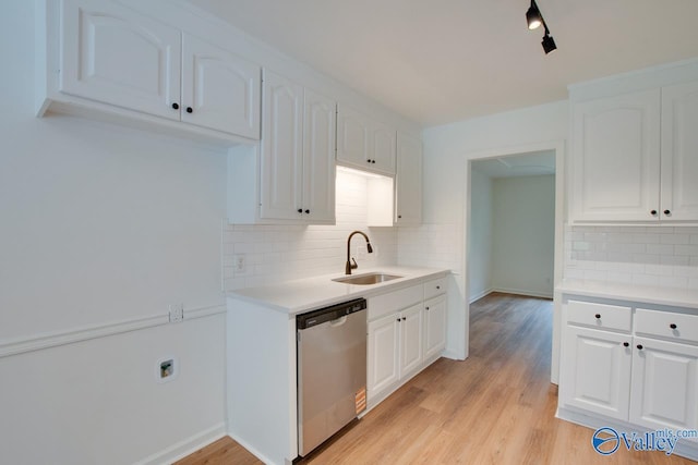 kitchen featuring decorative backsplash, stainless steel dishwasher, white cabinets, a sink, and light countertops