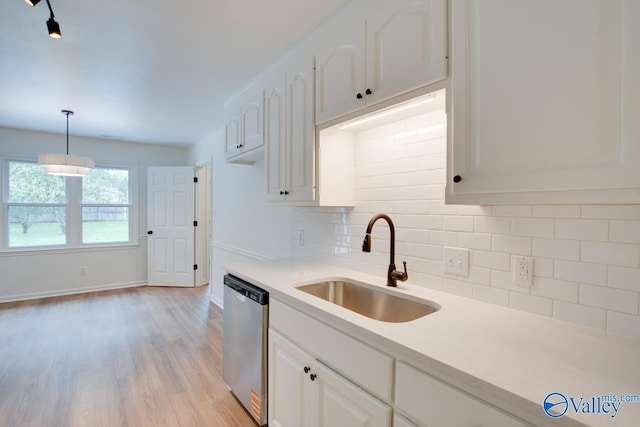kitchen featuring a sink, light wood-style floors, tasteful backsplash, white cabinetry, and dishwasher