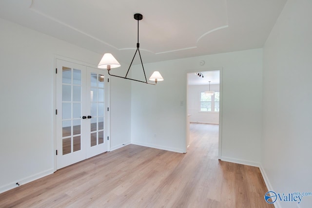 unfurnished dining area featuring wood finished floors, french doors, and baseboards