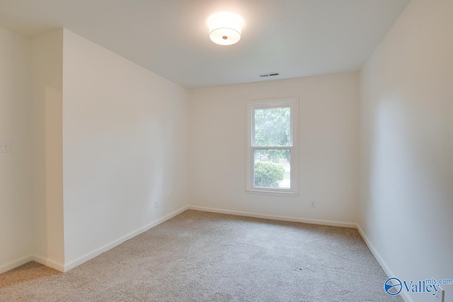 carpeted spare room featuring baseboards and visible vents