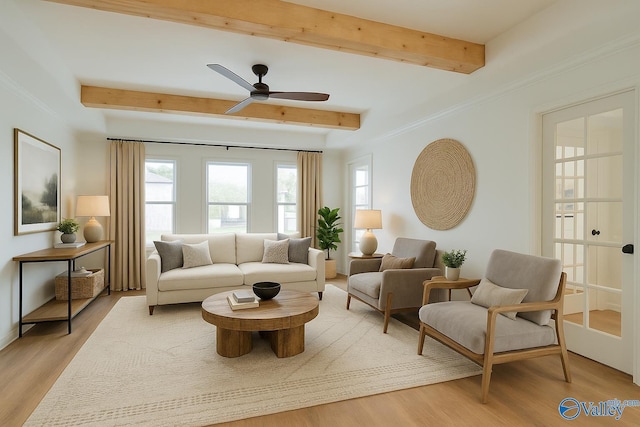 living room with a ceiling fan, light wood finished floors, and beamed ceiling