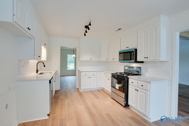 kitchen with tasteful backsplash, a sink, light wood-style floors, dishwasher, and gas stove