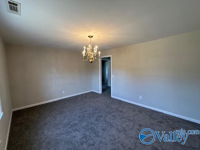 empty room with a chandelier and dark carpet