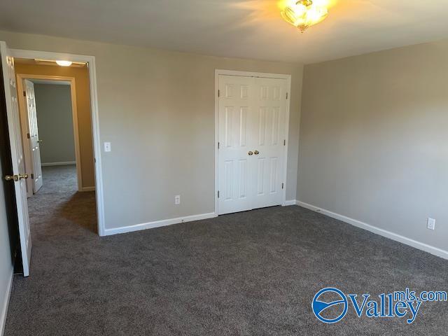 unfurnished bedroom featuring dark carpet and a closet